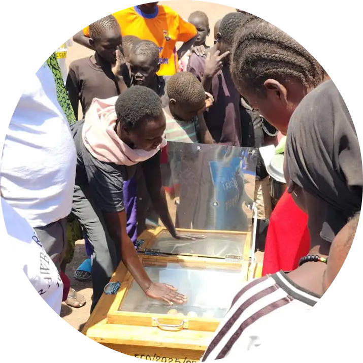 Family using a solar cooker outside their home in Kakuma Refugee Camp