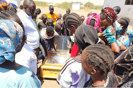 Group of SCI program participants gathered around solar cookers at a training site