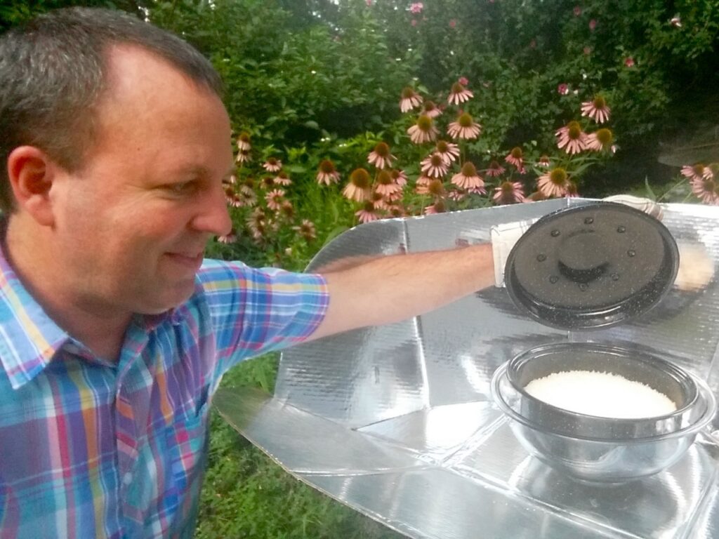 Alan Bigelow preparing food with a CooKit solar cooker outdoors